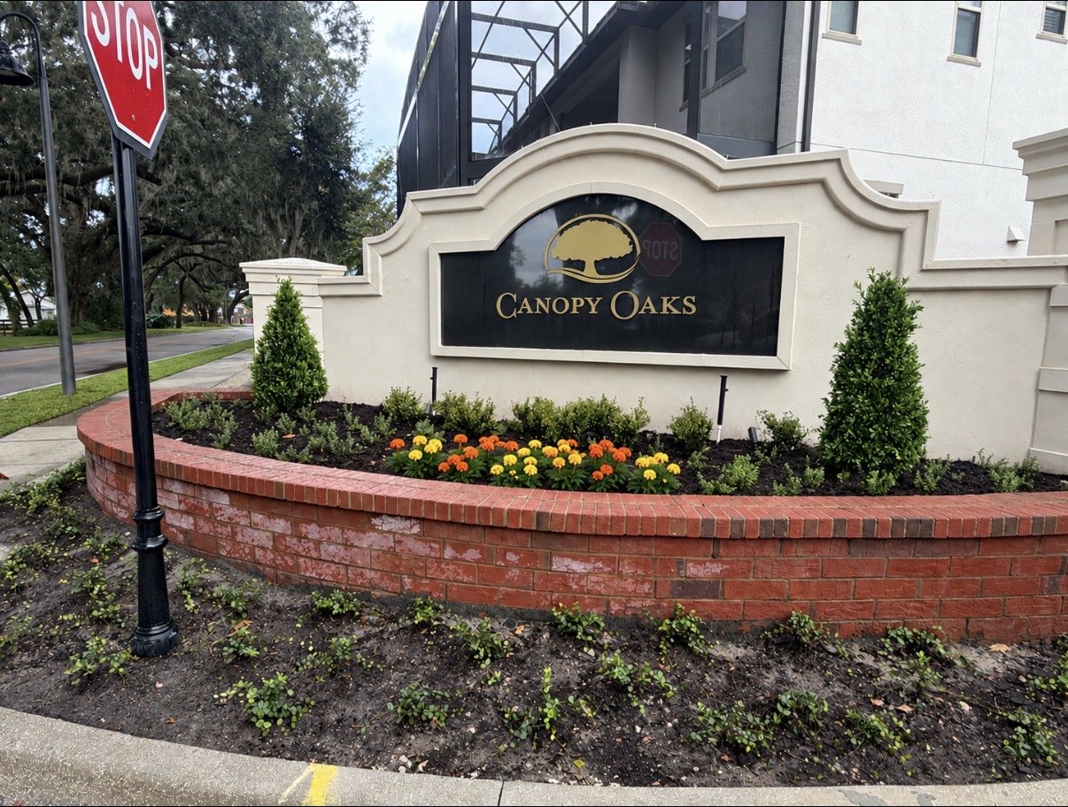 Canopy Oaks monument sign with new shrubs, evergreens and marigolds by Oakcrest Outdoors